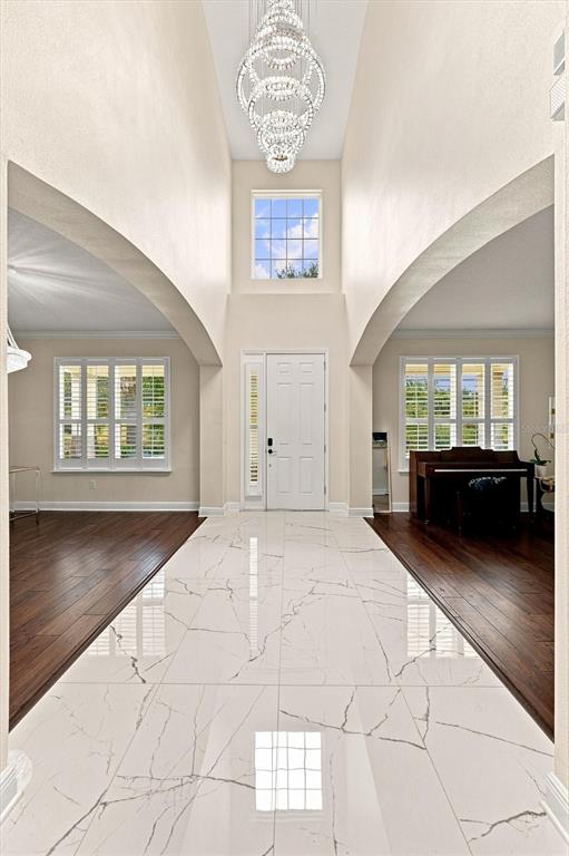 A bright entryway features white marble flooring, a tall crystal chandelier, and dark wood floors — 19902 WELLINGTON MANOR BOULEVARD, LUTZ, FL
