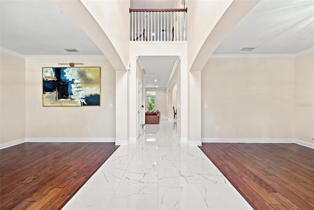 A foyer features white marble tile flooring, dark wood side floors, and a second-story balcony — 19902 WELLINGTON MANOR BOULEVARD, LUTZ, FL