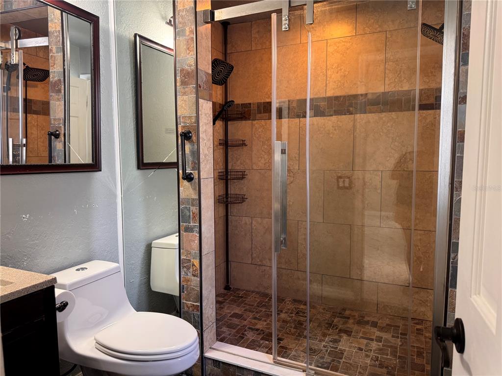 A bathroom features a tiled walk-in shower with a glass door next to a toilet — 9554 86TH AVENUE, SEMINOLE, FL