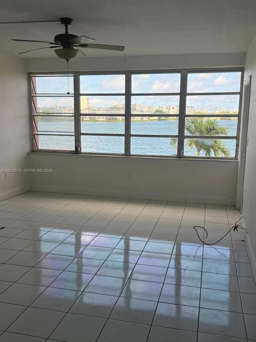 A room with white tile flooring, a ceiling fan, and large windows overlooking a body of water — 18555 NE 14th Ave # 615A, Miami FL 33179, MIAMI, FL