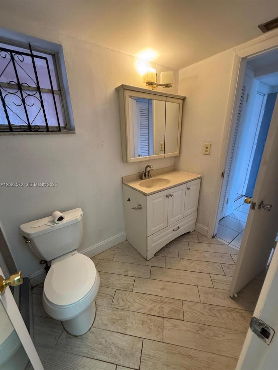 A bathroom features a white vanity, a medicine cabinet, a toilet, and light-colored wood-look flooring — 18555 NE 14th Ave # 615A, Miami FL 33179, MIAMI, FL