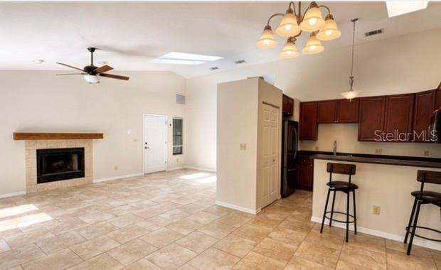 A kitchen with dark wood cabinets and a breakfast bar overlooks a tiled dining area — 3915 NW 7TH PLACE, GAINESVILLE, FL