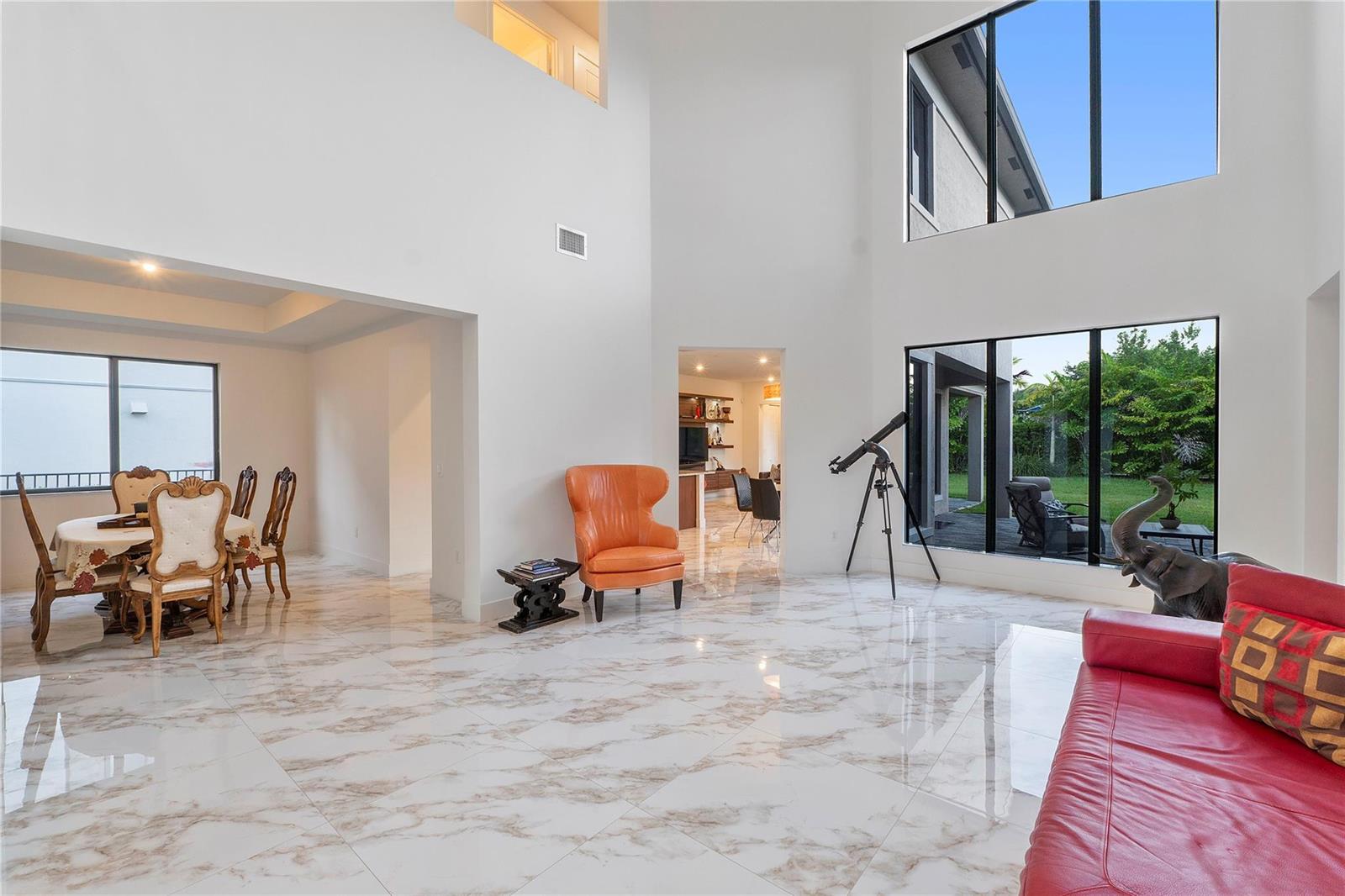 A spacious living room with high ceilings, marble floors, large windows, and a telescope — 10472 Cobalt Court, Parkland FL 33076, PARKLAND, FL