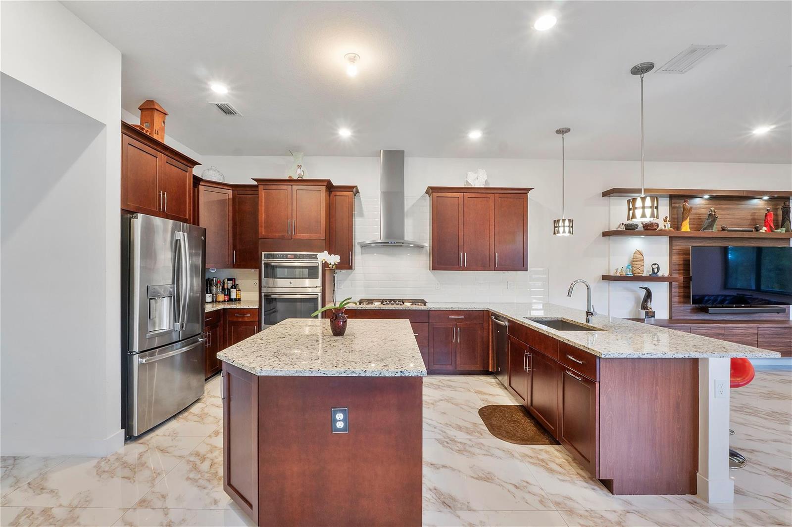 A kitchen with dark wood cabinets, granite countertops, stainless steel appliances, and marble-look tile flooring — 10472 Cobalt Court, Parkland FL 33076, PARKLAND, FL