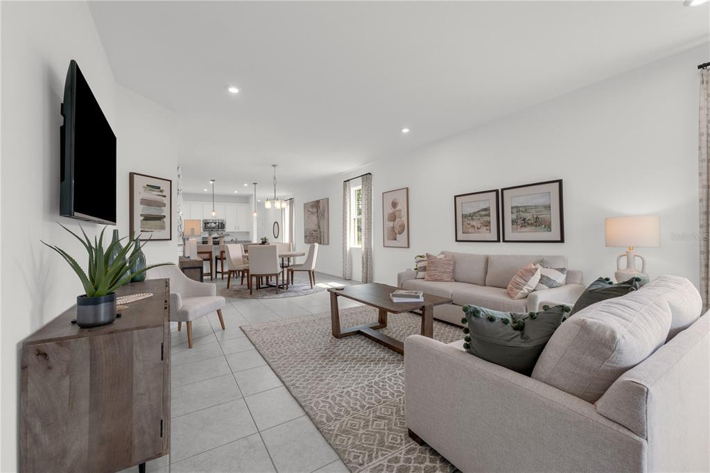An open-concept living and dining area features light-colored tile floors, neutral furniture, and white walls — 936 CASTLEFORD AVENUE NE, PALM BAY, FL