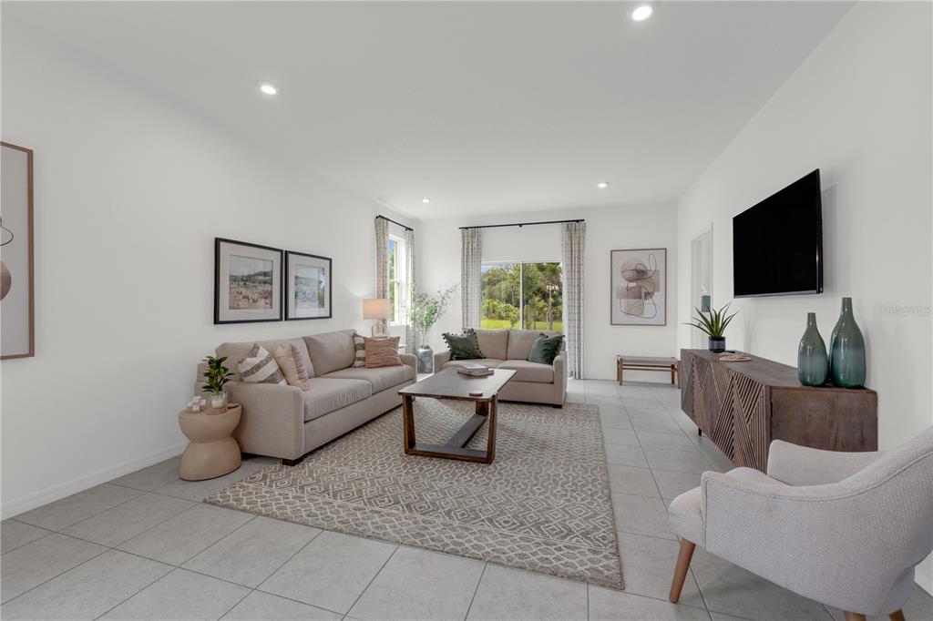 A bright living room features a beige sofa, a patterned area rug, and a television — 936 CASTLEFORD AVENUE NE, PALM BAY, FL