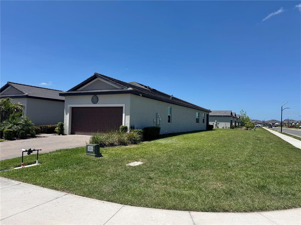 A single-story house with a brown garage door and a large side lawn — 12842 LILY QUARTZ LOOP, PARRISH, FL