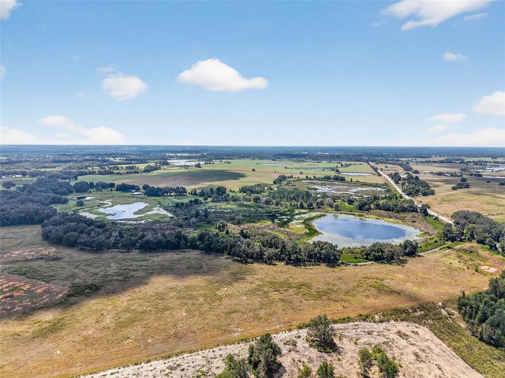 An aerial view shows a rural landscape with ponds, wooded areas, and open fields — COUNTY ROAD 48, GROVELAND, FL