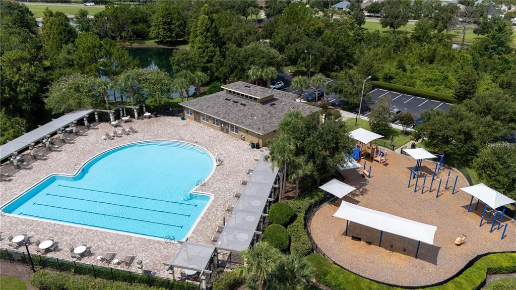 An aerial view shows a swimming pool, a clubhouse, and a playground with shaded structures — 4442 FENNWOOD COURT, WESLEY CHAPEL, FL
