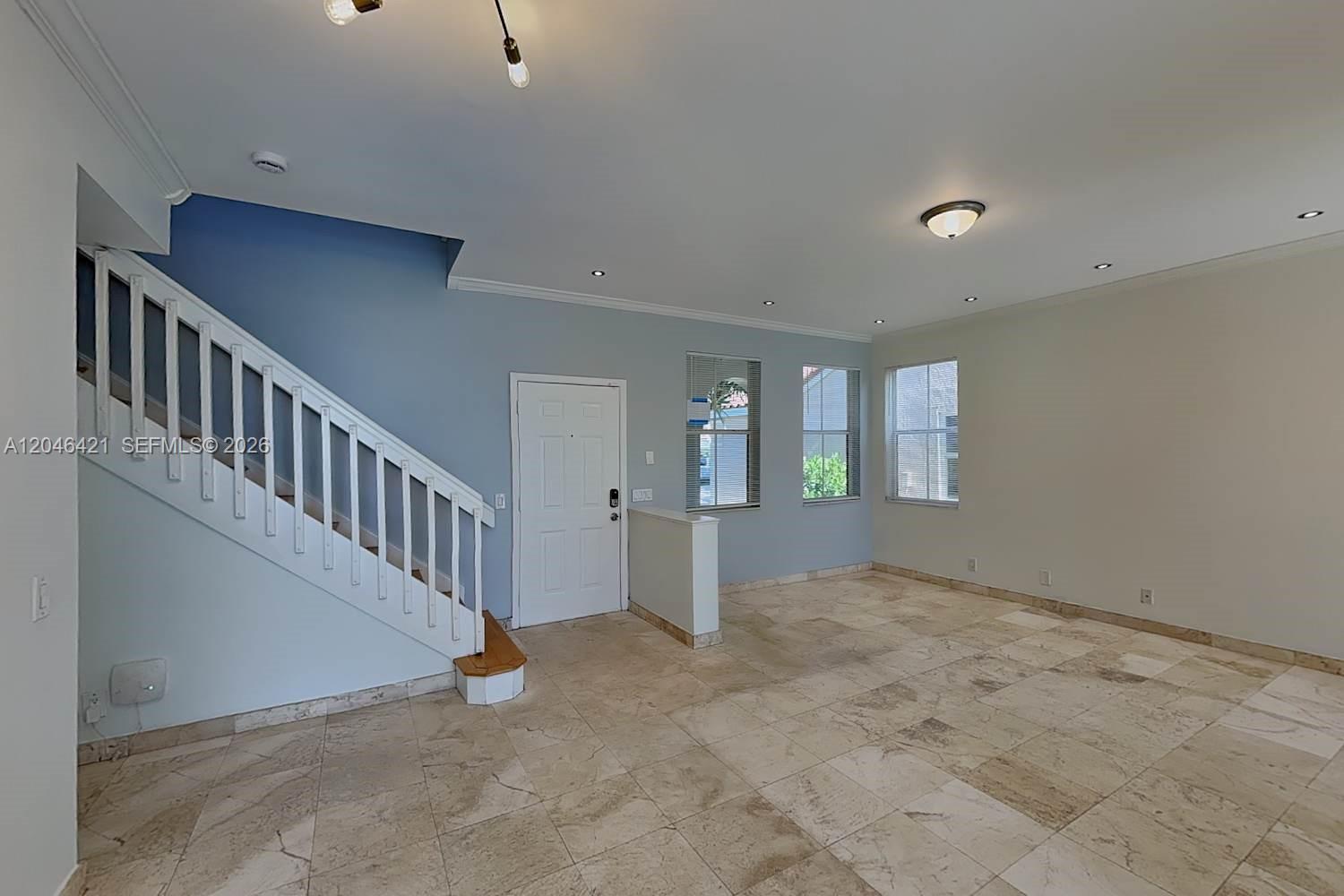An open living area features tiled floors, a white staircase, and a blue accent wall — WESTON, FL