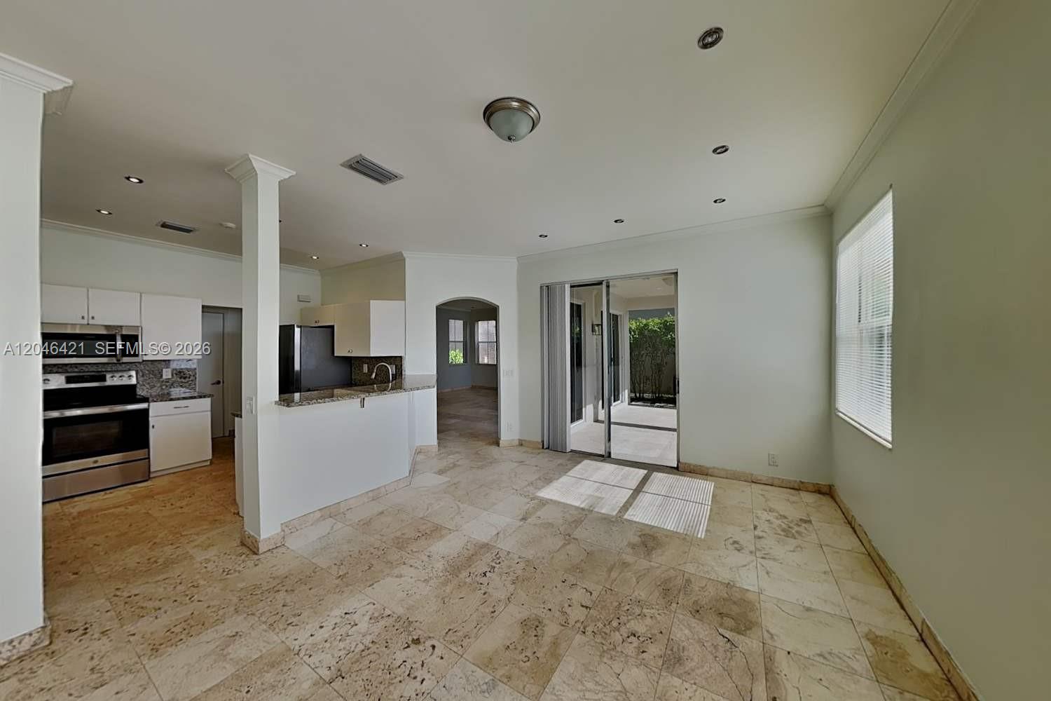 A kitchen with a breakfast bar opens into a dining area with tile flooring — WESTON, FL