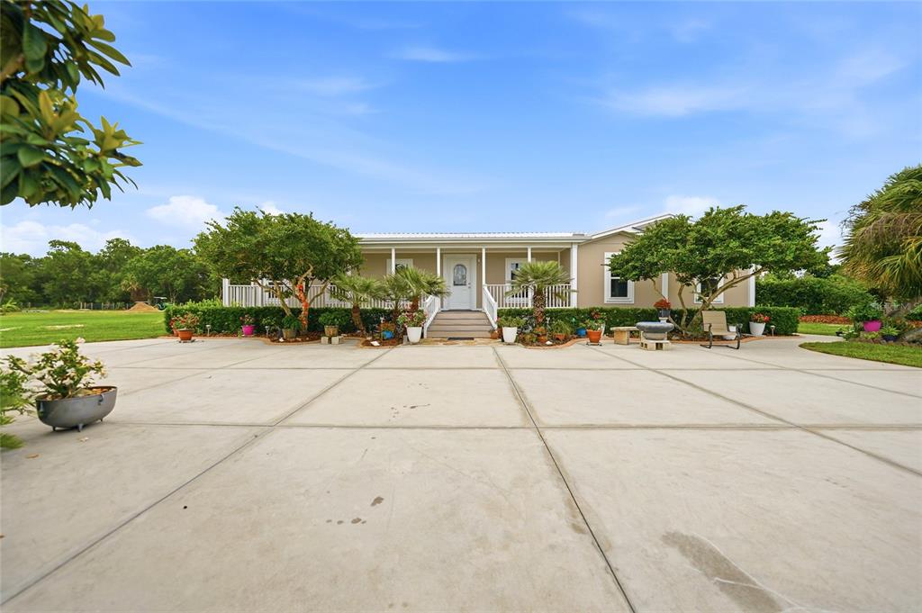 A single-story house with a large concrete driveway, front porch, and surrounding landscaping — 11354 SE SOUTH HOG BAY AVENUE, ARCADIA, FL