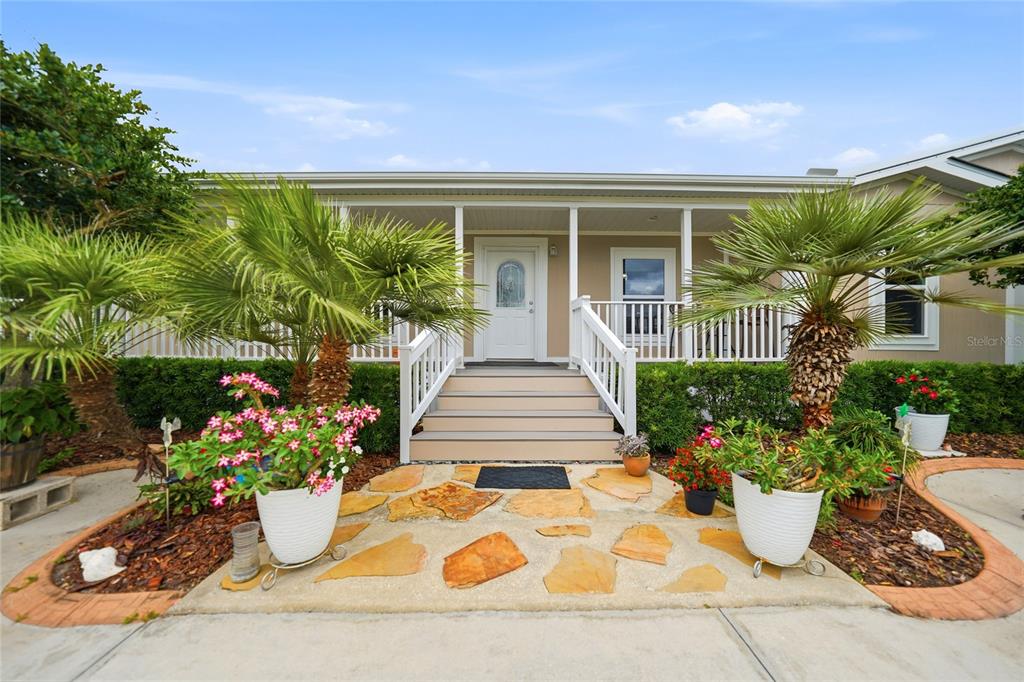 The exterior of a house features a front porch with stairs, palm trees, and landscaping — 11354 SE SOUTH HOG BAY AVENUE, ARCADIA, FL