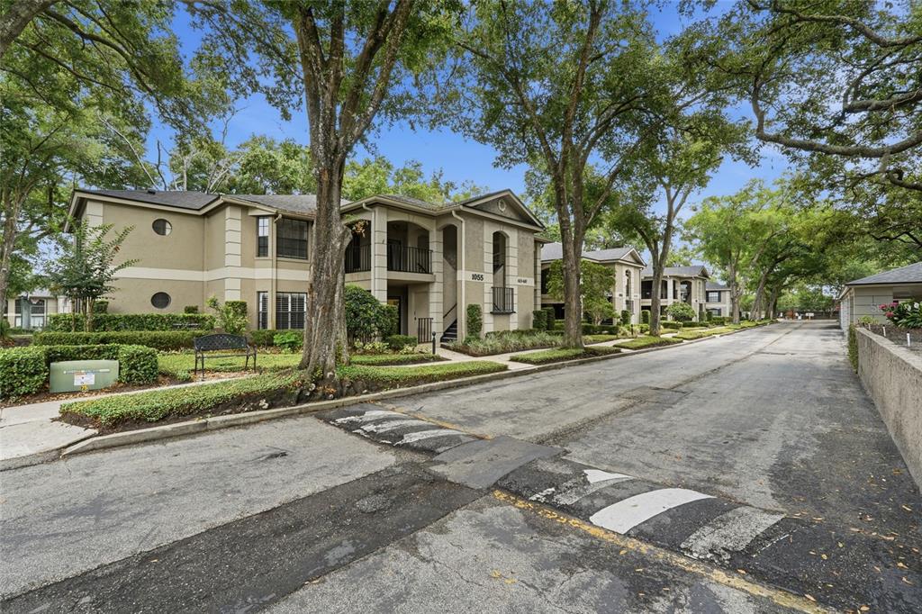 An exterior view of a multi-story apartment complex with trees and a speed bump — 1055 N KENSINGTON PARK DRIVE S UNIT 612, ALTAMONTE SPRINGS, FL