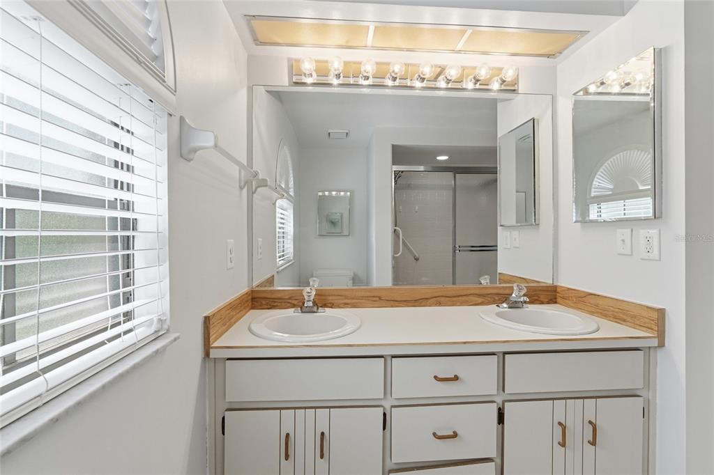 A bathroom with a double vanity, white cabinets, a large mirror, and a window — 1055 N KENSINGTON PARK DRIVE S UNIT 612, ALTAMONTE SPRINGS, FL