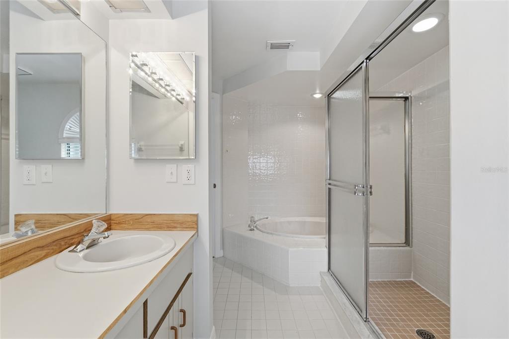 A bathroom features a vanity with a mirror, a soaking tub, and a glass-enclosed shower — 1055 N KENSINGTON PARK DRIVE S UNIT 612, ALTAMONTE SPRINGS, FL