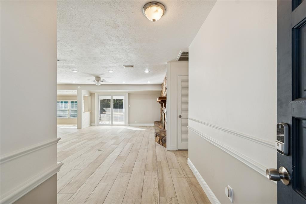 A living room features a stone fireplace, light wood flooring, and a sliding glass door — 9628 DAVIS ROAD, TAMPA, FL