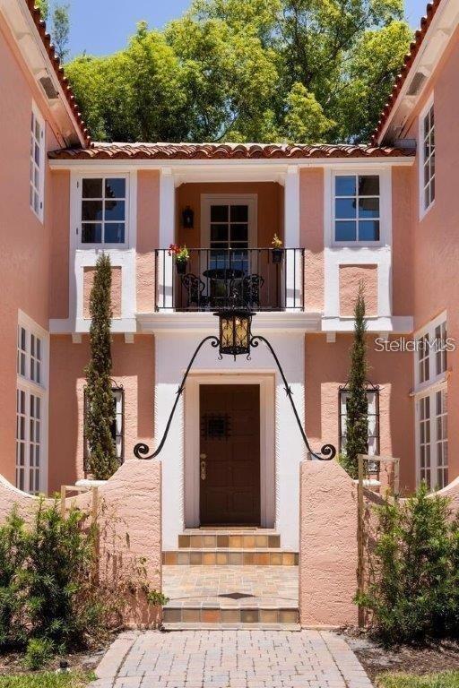 A peach-colored stucco house features a central front door, a balcony, and symmetrical landscaping — 4511 BAY SHORE ROAD, SARASOTA, FL