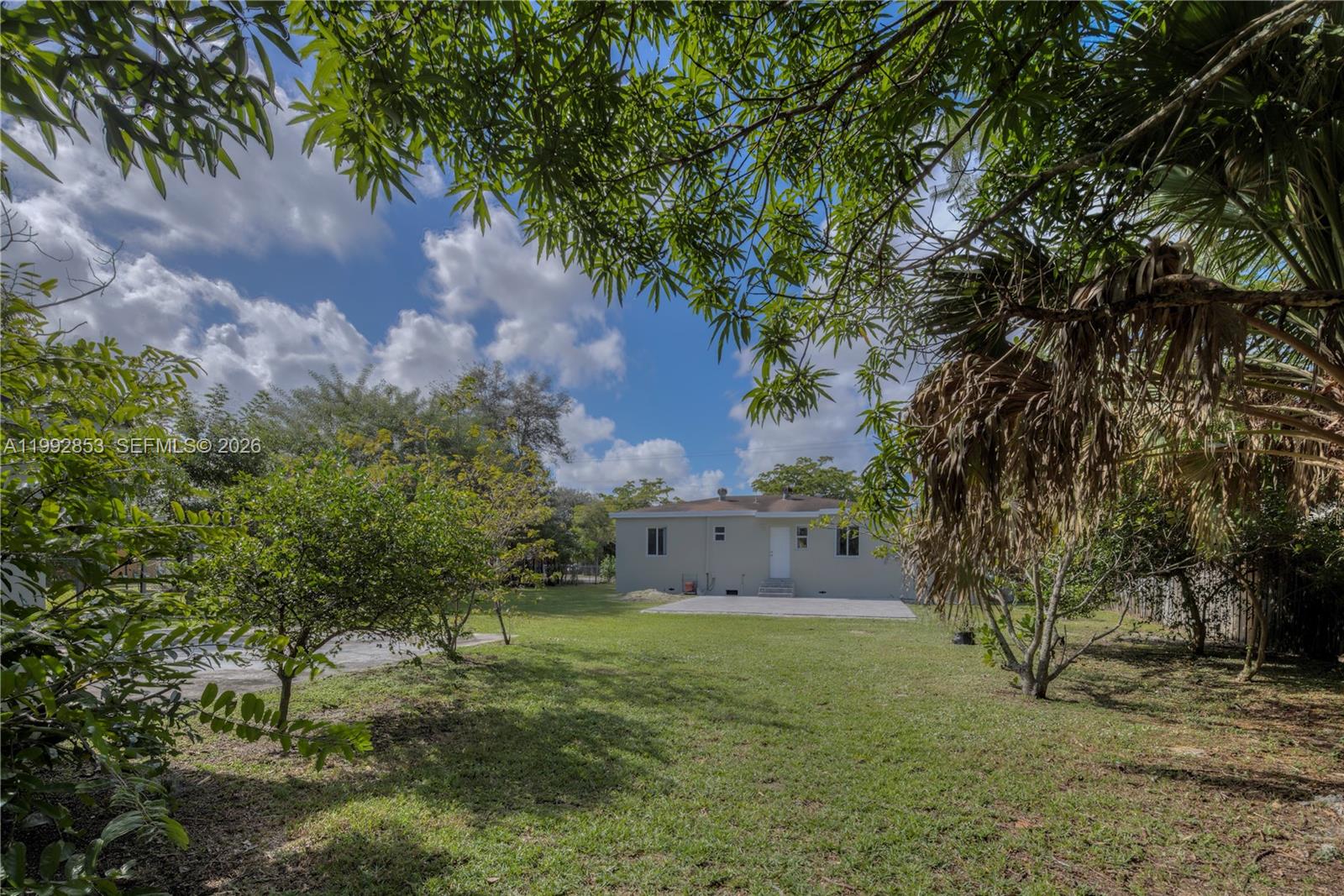 A view of a backyard with a lawn, trees, and the rear of a house — 14115 NW 5th Ave # 1, Miami FL 33168, MIAMI, FL