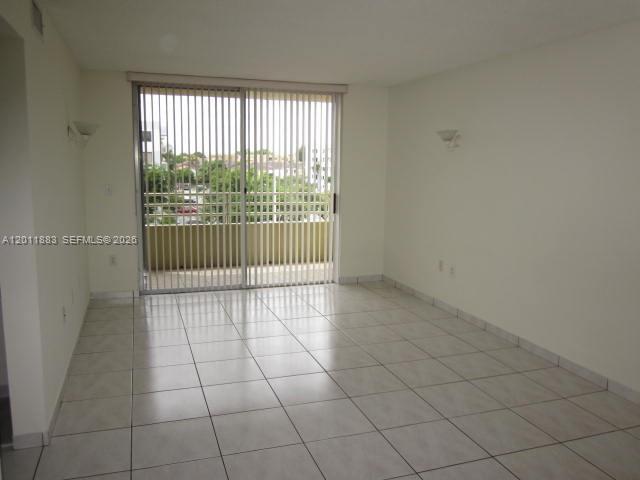 An empty room features white tiled floors, plain walls, and a sliding glass door — 8201 NW 8th St # 414, Miami FL 33126, MIAMI, FL