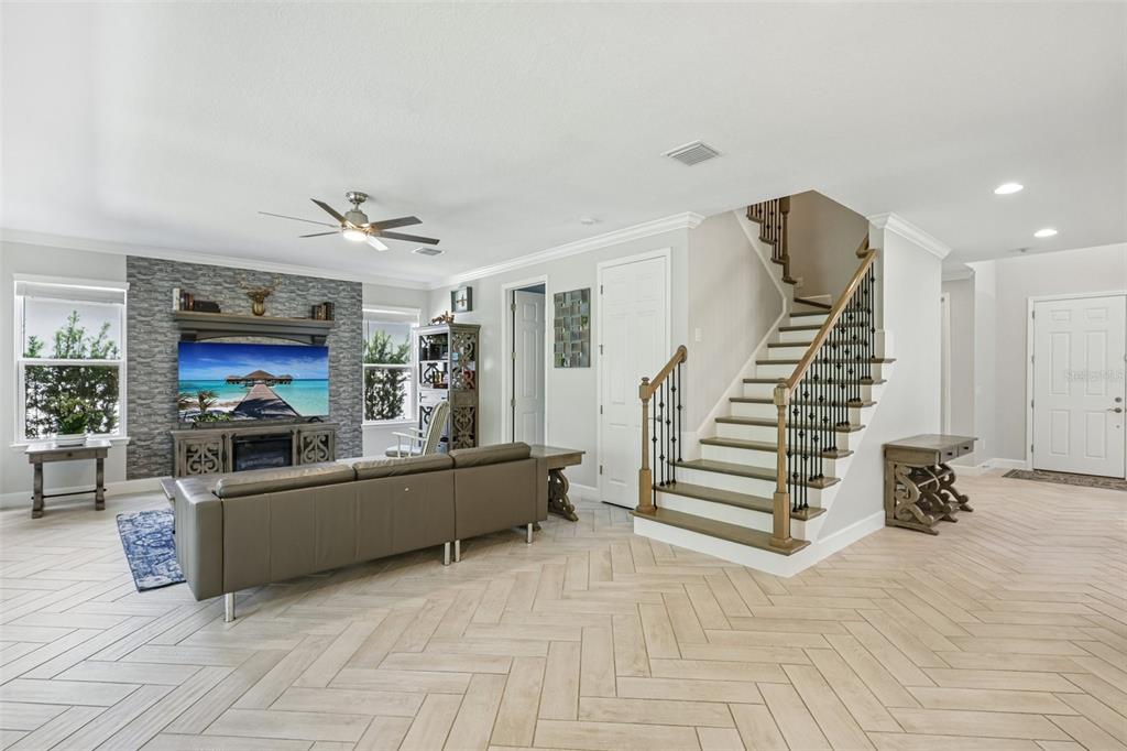 A living room features a stone fireplace, a staircase with iron railings, and herringbone flooring — 9085 SPRUCE CREEK CIRCLE, RIVERVIEW, FL
