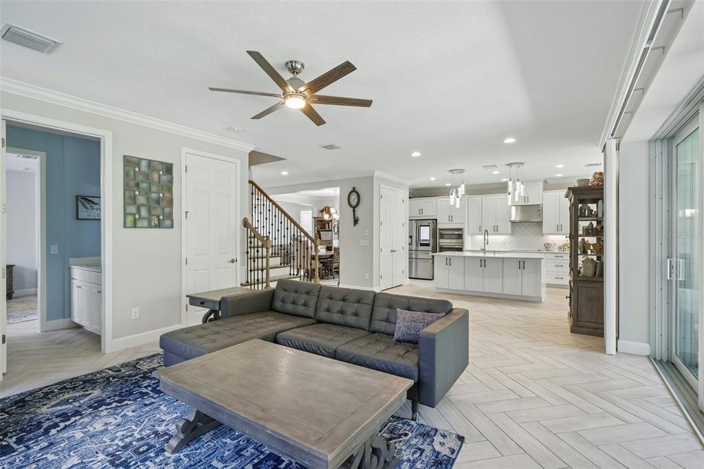 A living room with a grey sectional sofa opens into a white kitchen with an island — 9085 SPRUCE CREEK CIRCLE, RIVERVIEW, FL