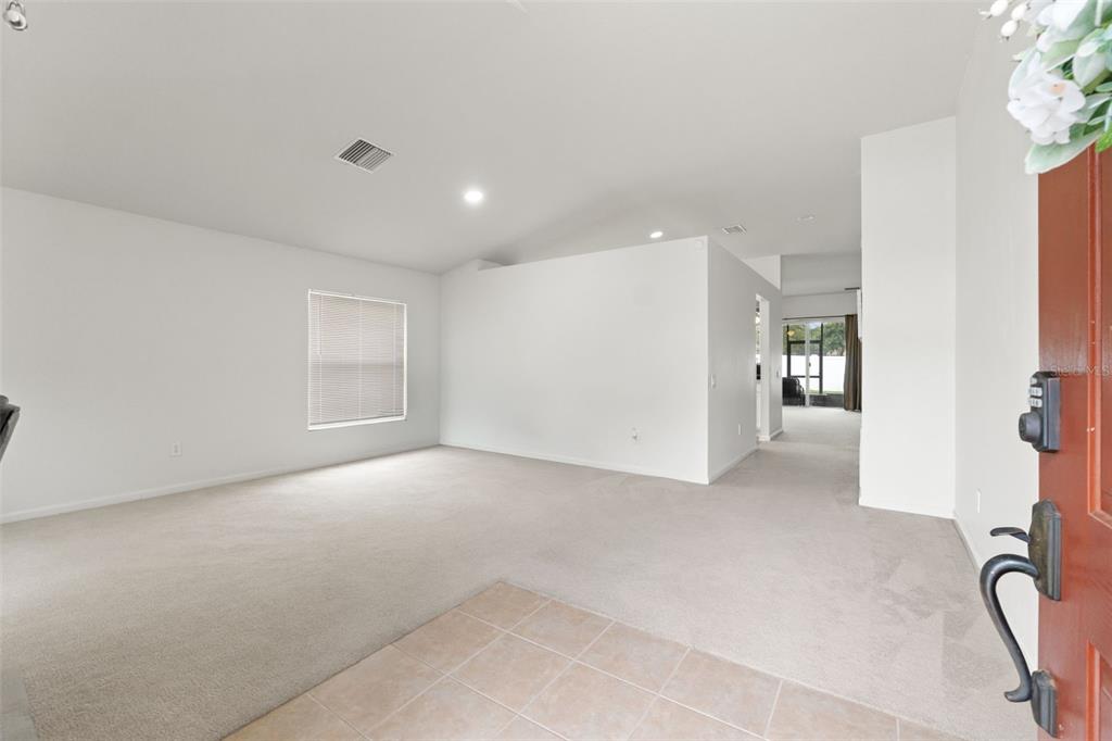 An entryway with tile flooring leads into a carpeted living area with white walls — 14450 WAKE ROBIN DRIVE, BROOKSVILLE, FL