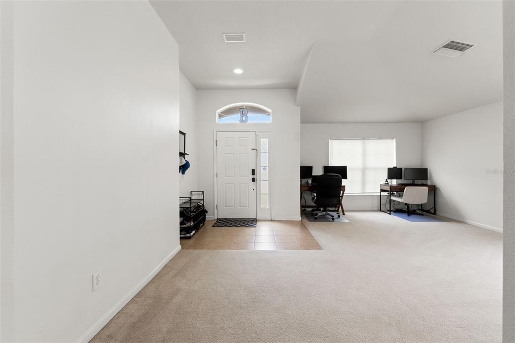 An entryway with tile flooring leads into a carpeted room featuring two desk workstations — 14450 WAKE ROBIN DRIVE, BROOKSVILLE, FL