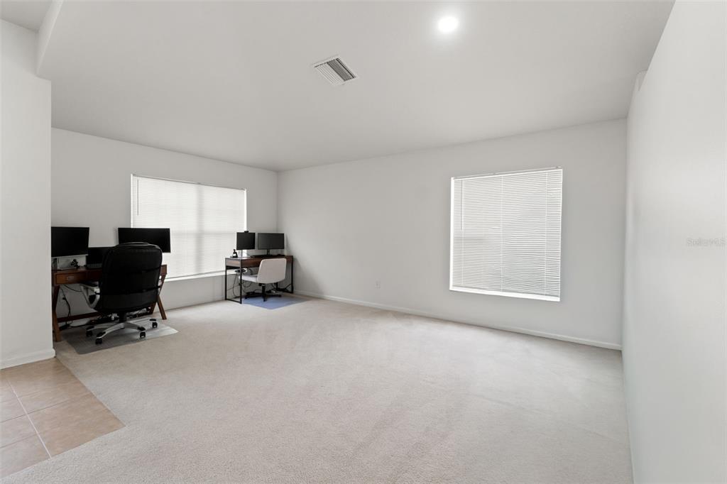 A spacious room with beige carpeting, white walls, and two desks positioned near windows — 14450 WAKE ROBIN DRIVE, BROOKSVILLE, FL