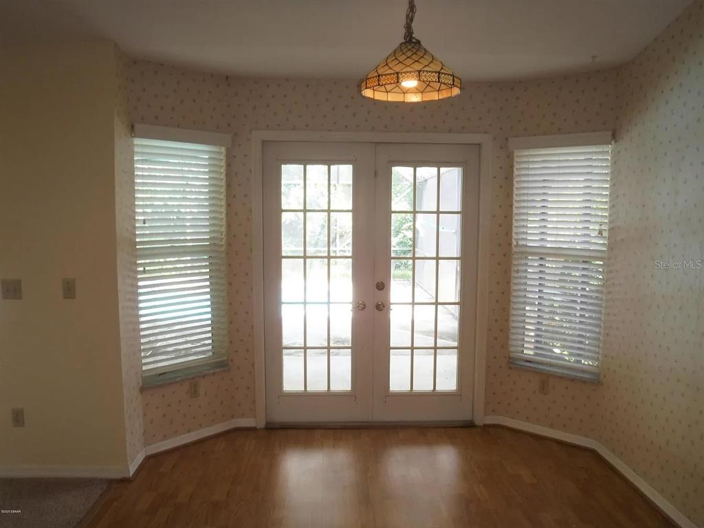 A dining area with hardwood floors, wallpaper, a hanging light fixture, and French doors — 105 MARBLED GODWIT COURT, DAYTONA BEACH, FL