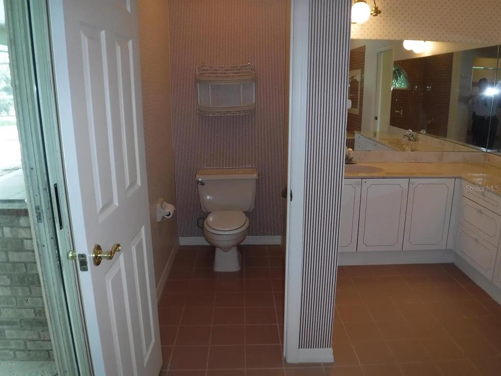 A bathroom features a toilet in a small alcove next to a vanity with cabinets — 105 MARBLED GODWIT COURT, DAYTONA BEACH, FL