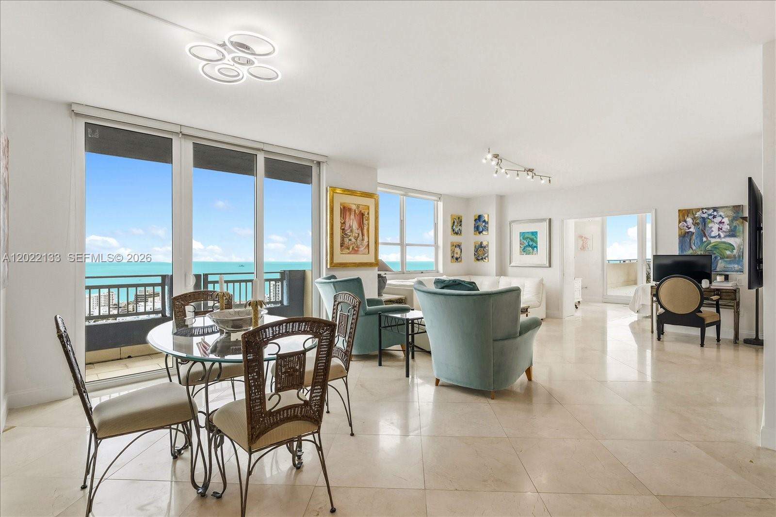 A bright living and dining area features tile floors, ocean views, and balcony access — 90 Alton Rd, Miami Beach FL 33139, MIAMI BEACH, FL