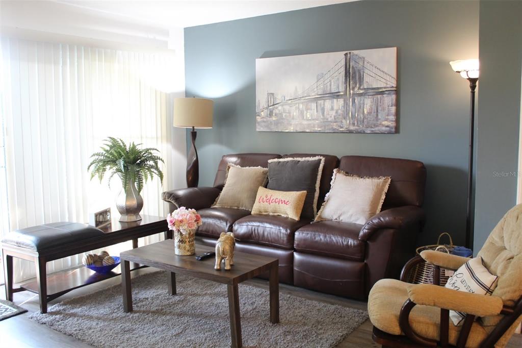 A living room features a brown leather sofa, a coffee table, and a bridge painting — 1222 VILLA LANE UNIT 136, APOPKA, FL