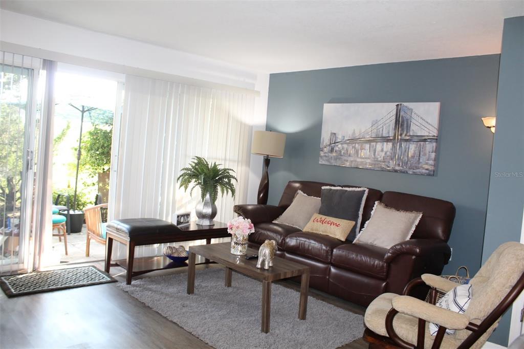 A living room features a brown leather sofa, a coffee table, and a blue accent wall — 1222 VILLA LANE UNIT 136, APOPKA, FL
