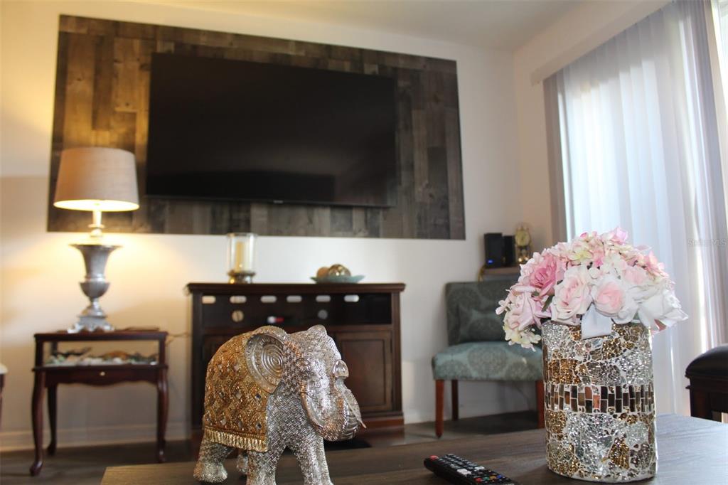 A living room features a wall-mounted television on a reclaimed wood accent wall — 1222 VILLA LANE UNIT 136, APOPKA, FL