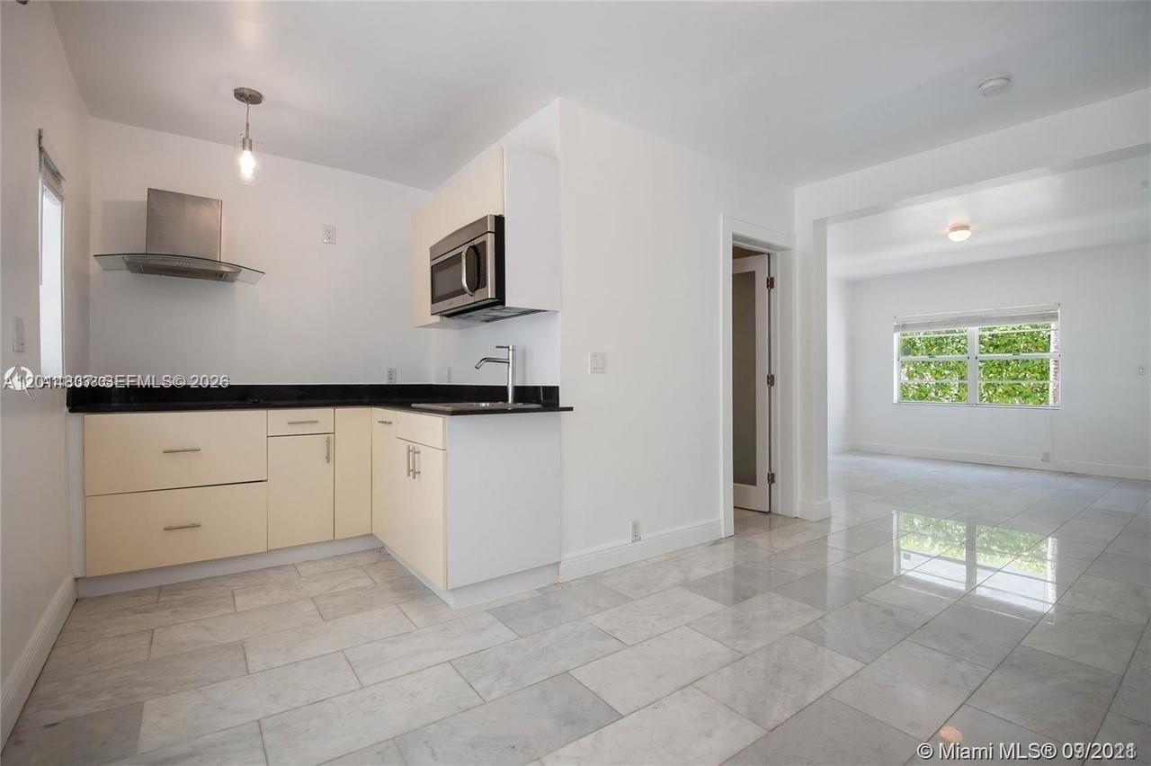 A kitchen with light-colored cabinets, a black countertop, and a stainless steel range hood — 928 Jefferson Ave, Miami Beach FL 33139, MIAMI BEACH, FL