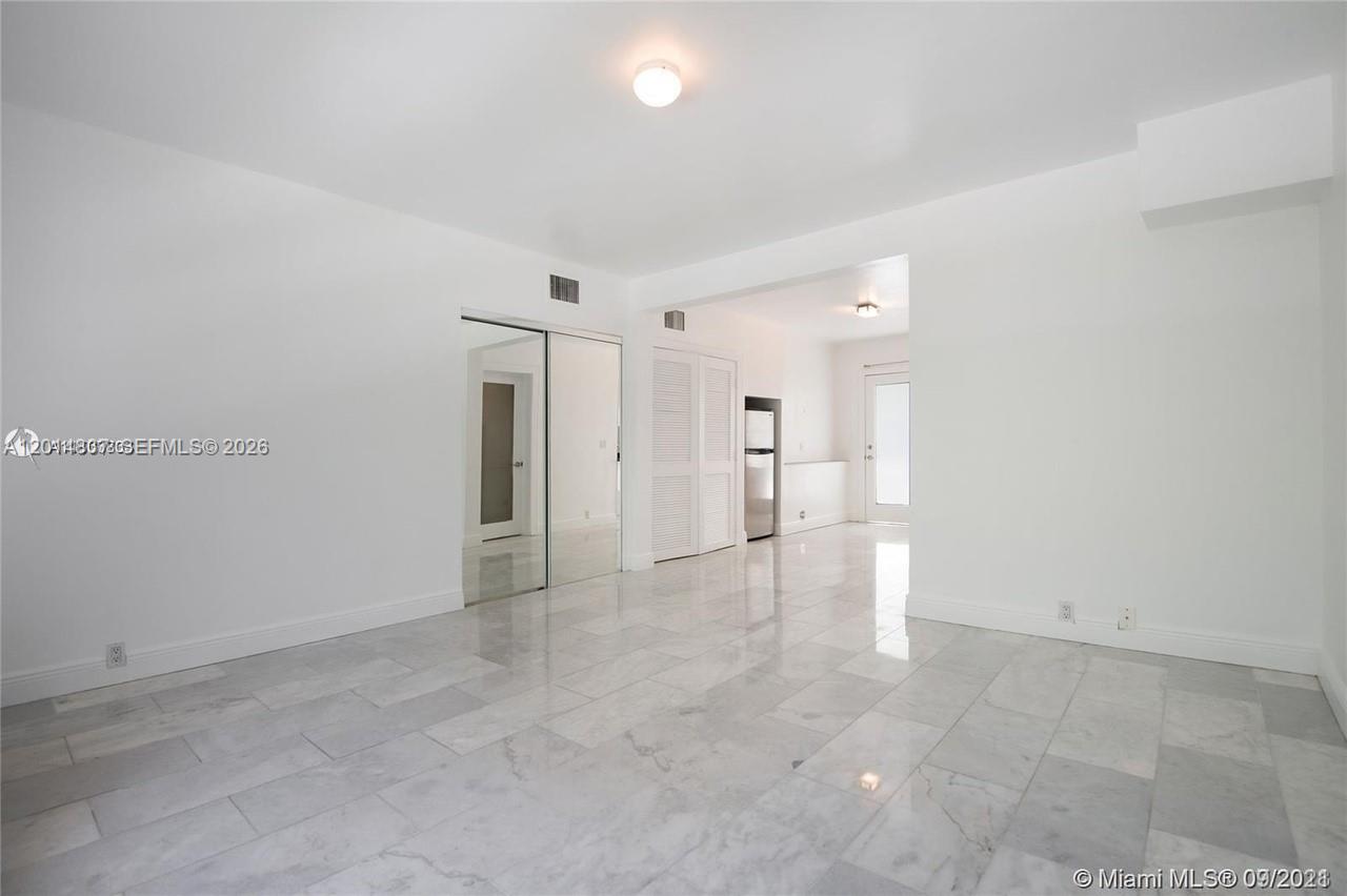 A bright, empty room features white walls, marble flooring, and a mirrored closet — 928 Jefferson Ave, Miami Beach FL 33139, MIAMI BEACH, FL