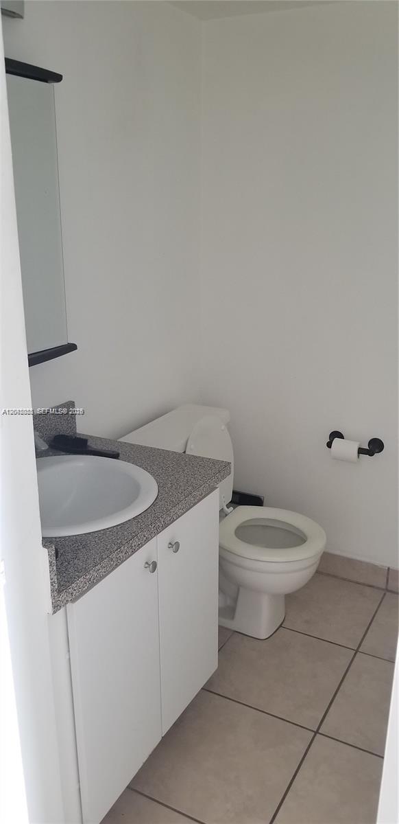 A small bathroom features a white vanity with a speckled countertop and a toilet — 13155 Ixora Ct # 810, North Miami FL 33181, NORTH MIAMI, FL