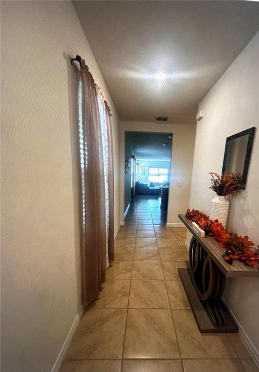 A tiled hallway features a console table with autumn decor and a curtained window — 1396 BERRY LANE, DAVENPORT, FL