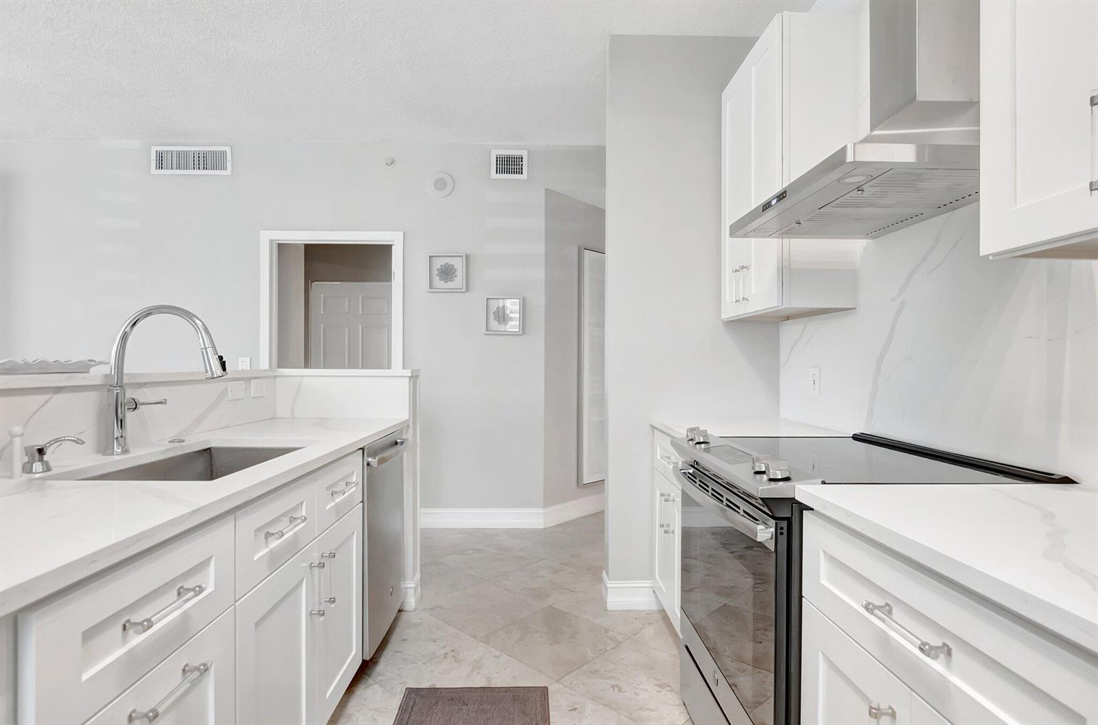 A modern kitchen features white cabinetry, stainless steel appliances, and light-colored countertops — 3606 S Ocean Boulevard # 108, Highland Beach FL 33487, HIGHLAND BEACH, FL