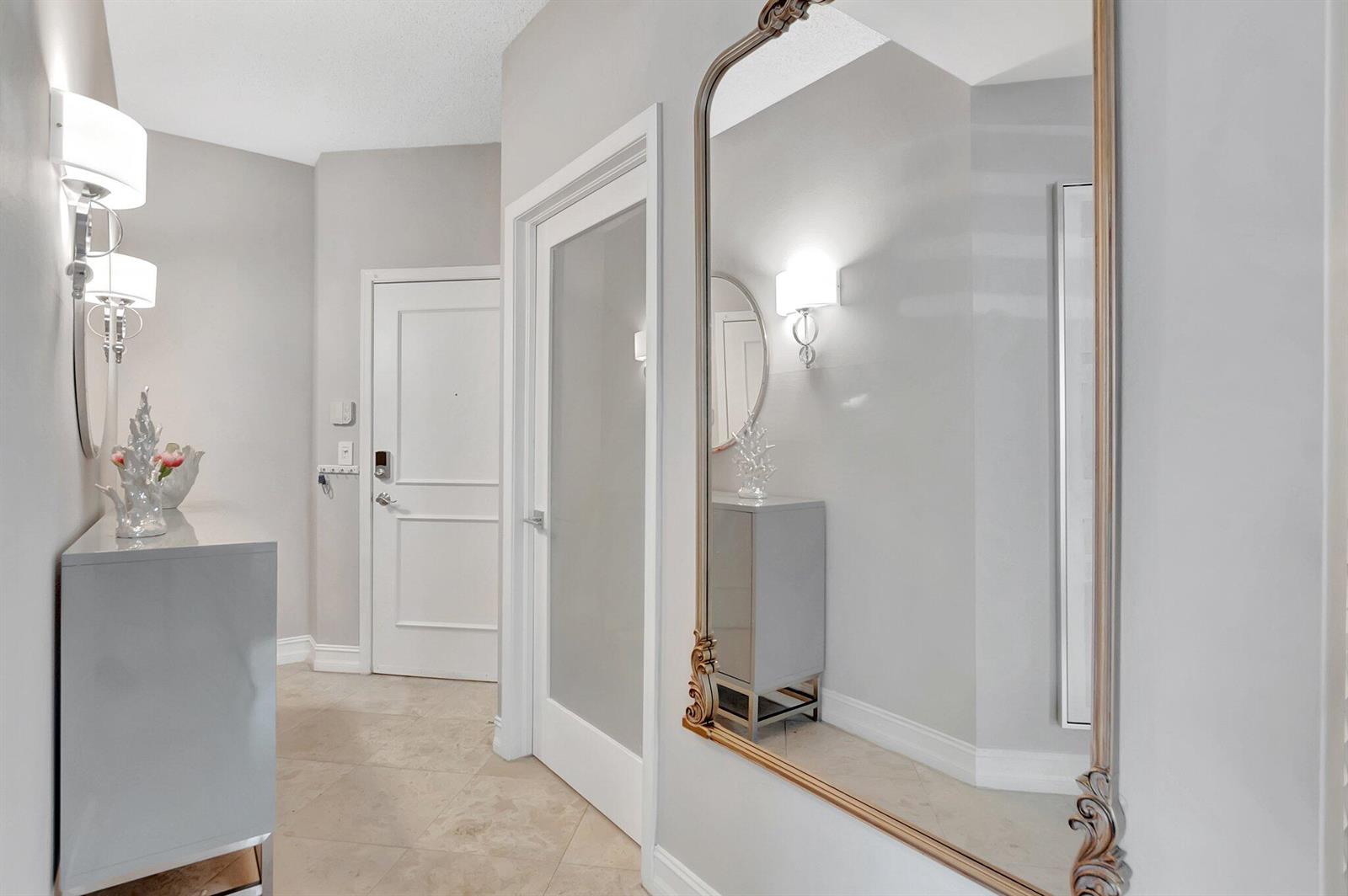 A bright entryway features a large ornate mirror, a console table, and white doors — 3606 S Ocean Boulevard # 108, Highland Beach FL 33487, HIGHLAND BEACH, FL