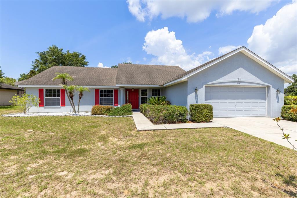 A single-story house with a light blue exterior, red shutters, and an attached two-car garage — 4450 TREASURE CAY ROAD, TAVARES, FL