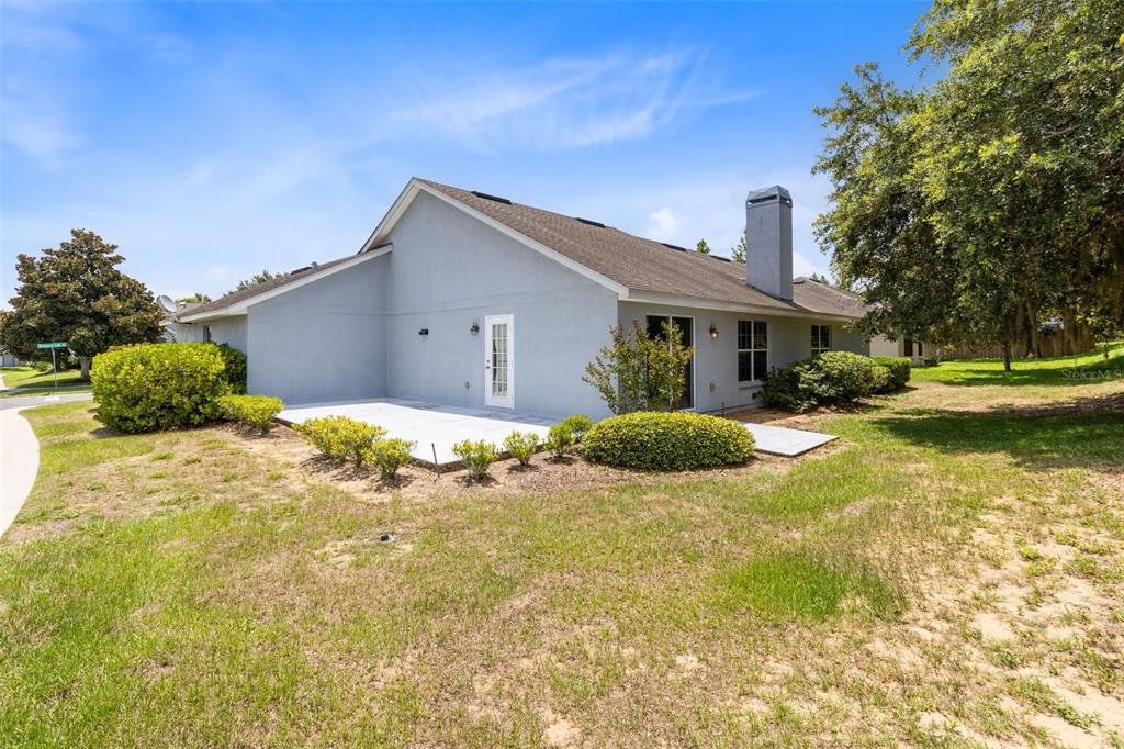 The exterior of a gray house features a concrete patio, a chimney, and landscaping — 4450 TREASURE CAY ROAD, TAVARES, FL
