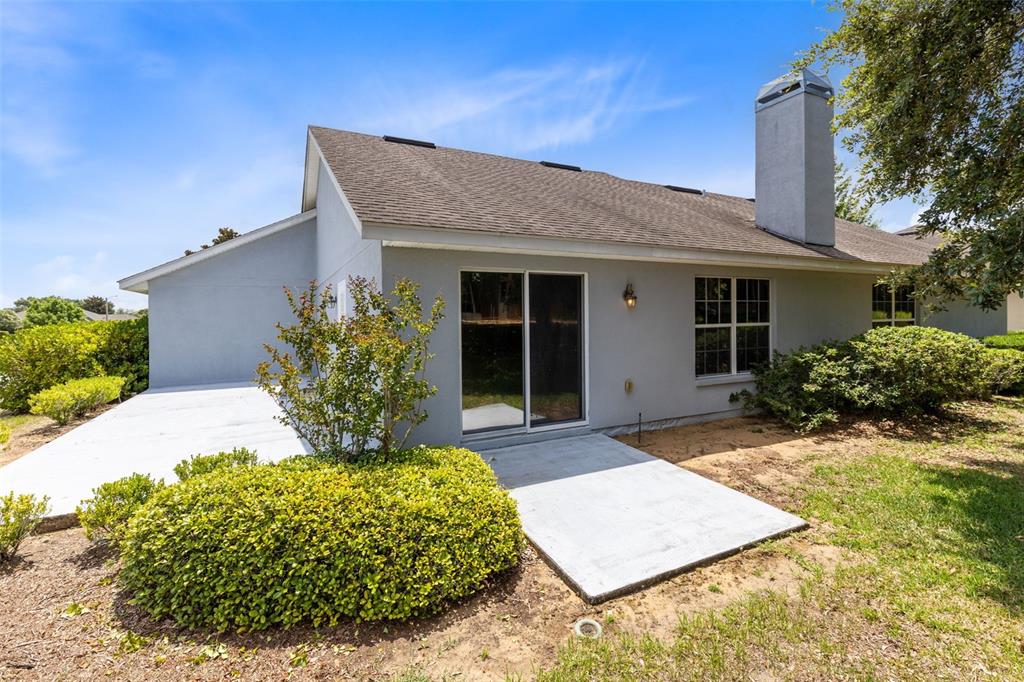 The exterior of a gray house features a concrete patio, sliding glass doors, and chimney — 4450 TREASURE CAY ROAD, TAVARES, FL
