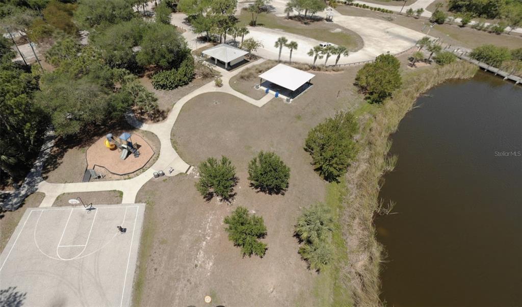 An aerial view of a park featuring a basketball court, playground, picnic pavilions, and pond — 13879 BEGONIA CIRCLE, PORT CHARLOTTE, FL