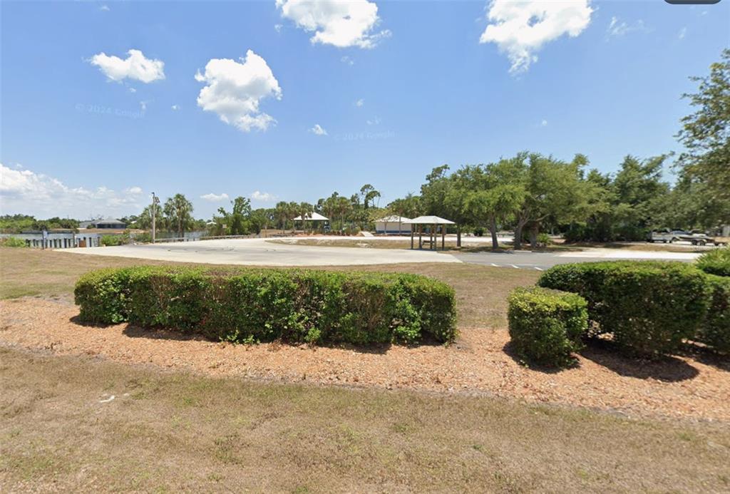 A paved parking area sits in front of a park with trees and a pavilion — 13879 BEGONIA CIRCLE, PORT CHARLOTTE, FL