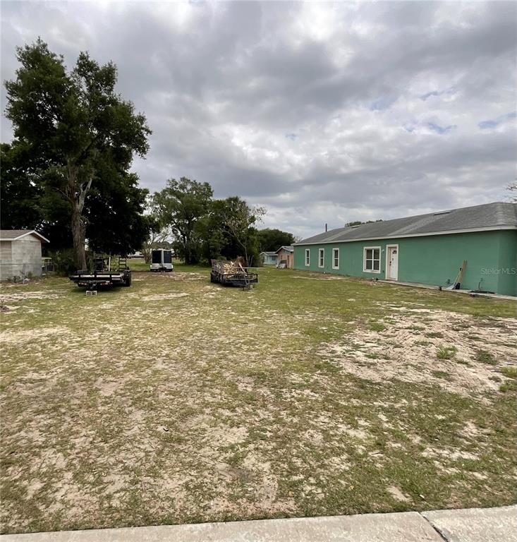 A green house sits on a large, grassy lot with two trailers parked in the yard — 480 D STREET, LAKE WALES, FL