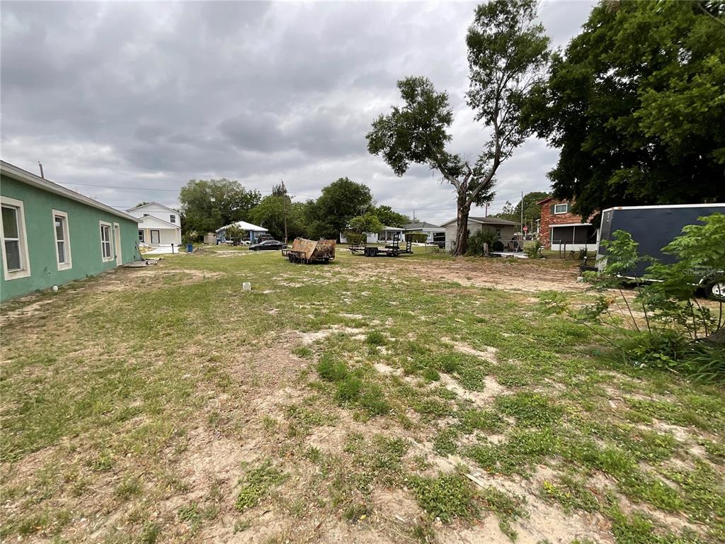 A large, grassy vacant lot sits next to a green house under a cloudy sky — 480 D STREET, LAKE WALES, FL