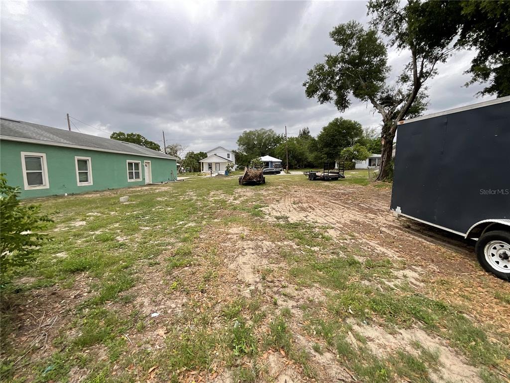 A large, grassy vacant lot features a green house and a parked trailer — 480 D STREET, LAKE WALES, FL