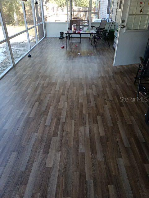 A sunroom features wood-look flooring, large windows, and a small table with chairs — 2042 S SUNWOOD POINT, HOMOSASSA, FL